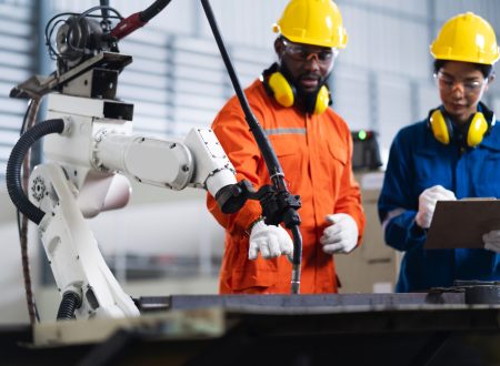 engineer cooperation male and female technician maintenance control relay robot arm system welding with tablet laptop to control quality operate process work heavy industry 4.0 manufacturing factory